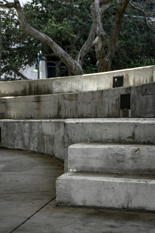 two skateboarders jumping over concrete stairs near trees