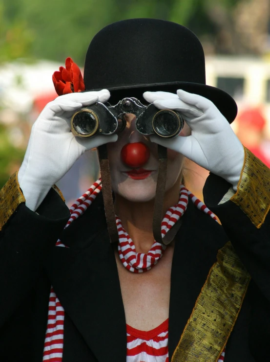 a clown wearing a top hat and holding a pair of binoculars