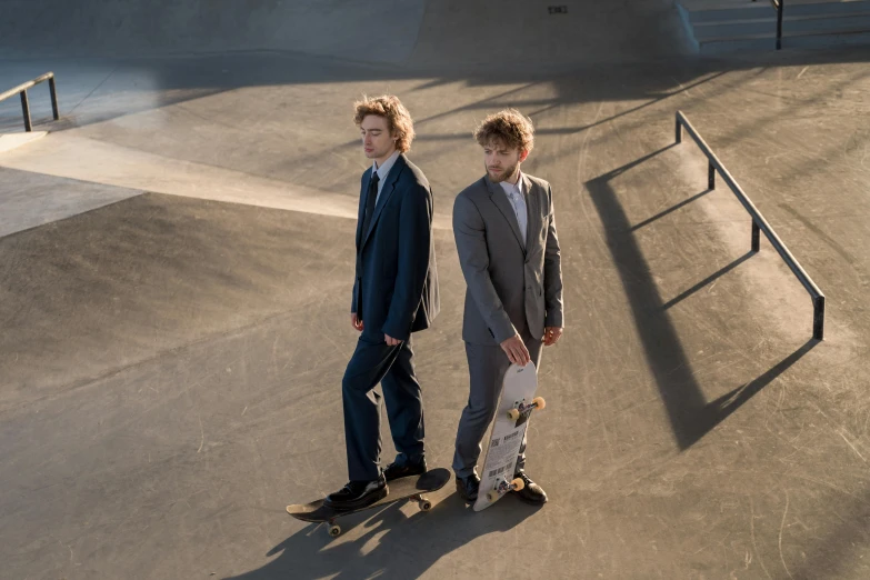 two s standing in a skate park and one is on a skateboard