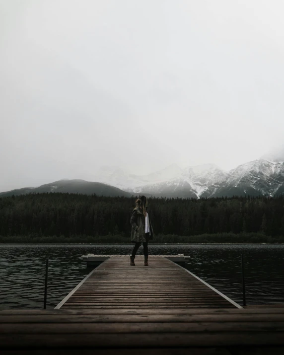 a man standing on top of a dock next to a forest