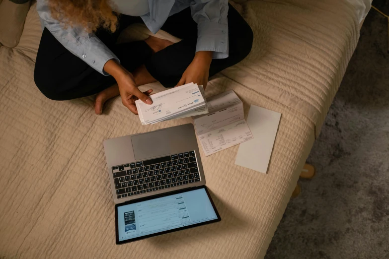 a person sitting on the bed and checking out some documents