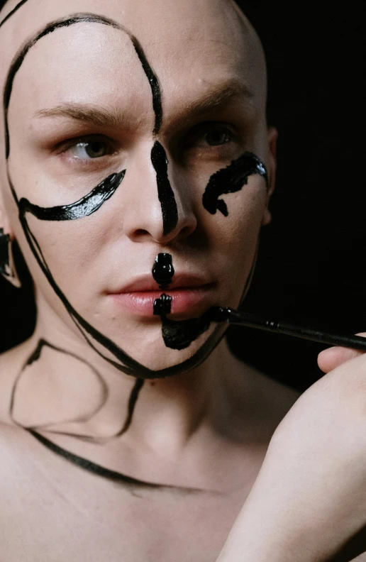 a man with painted face putting makeup on his nose