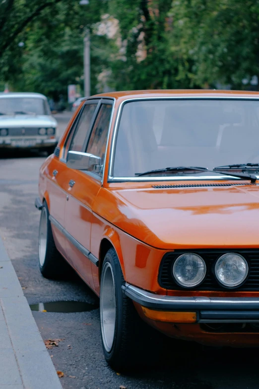 an orange car parked along a street in the city