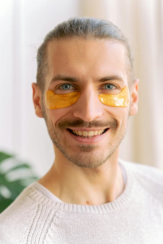 a young man is smiling while wearing plastic eye masks