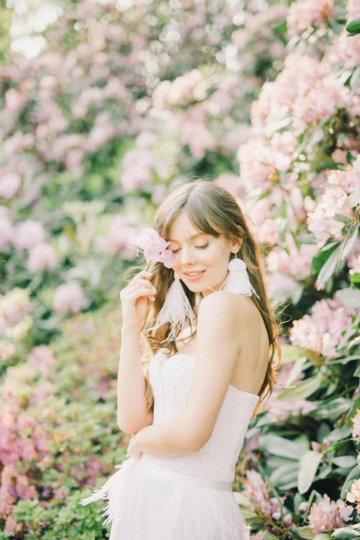 a  in white dress holding a pink flower and a white background