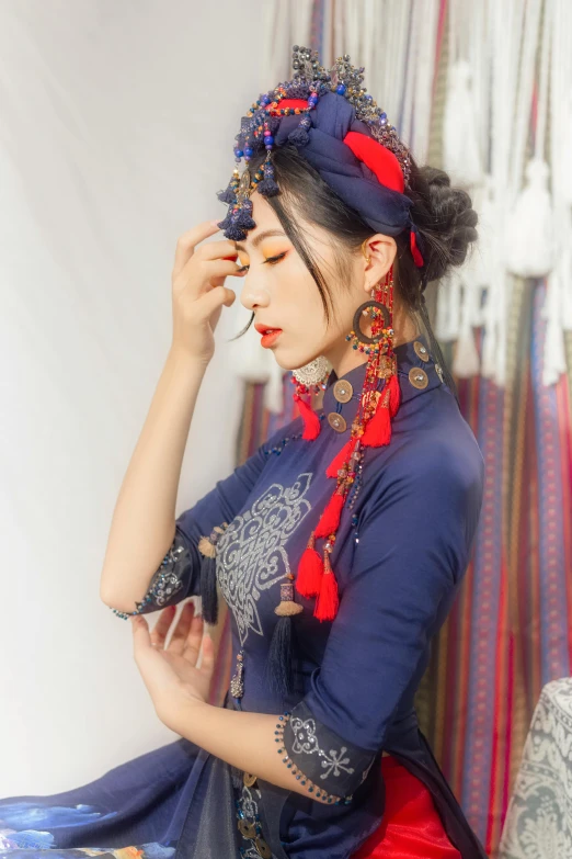 woman wearing oriental dress looking down with hands on forehead