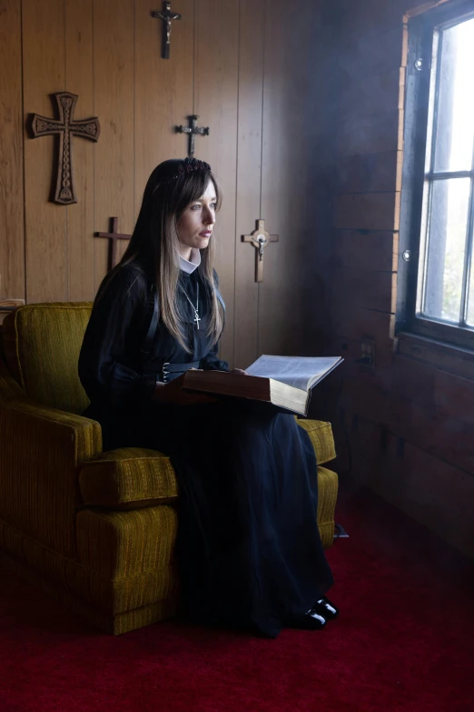 a woman sitting in a chair while reading a book