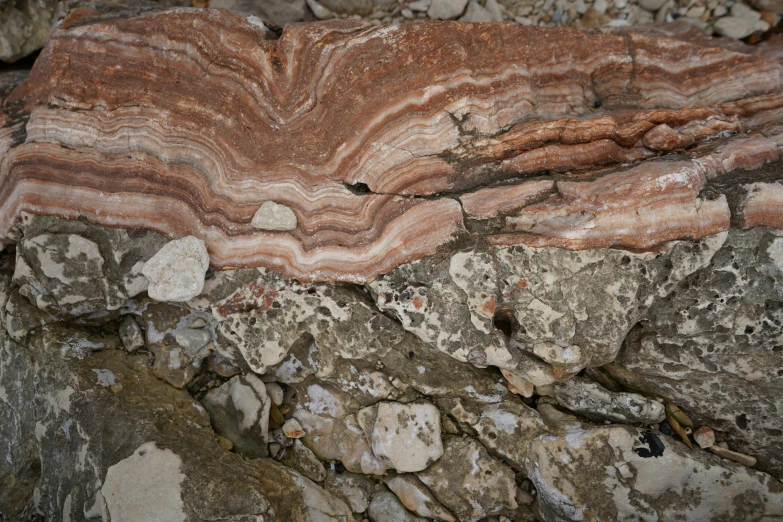 red, brown and white rock that is next to a pile of rocks