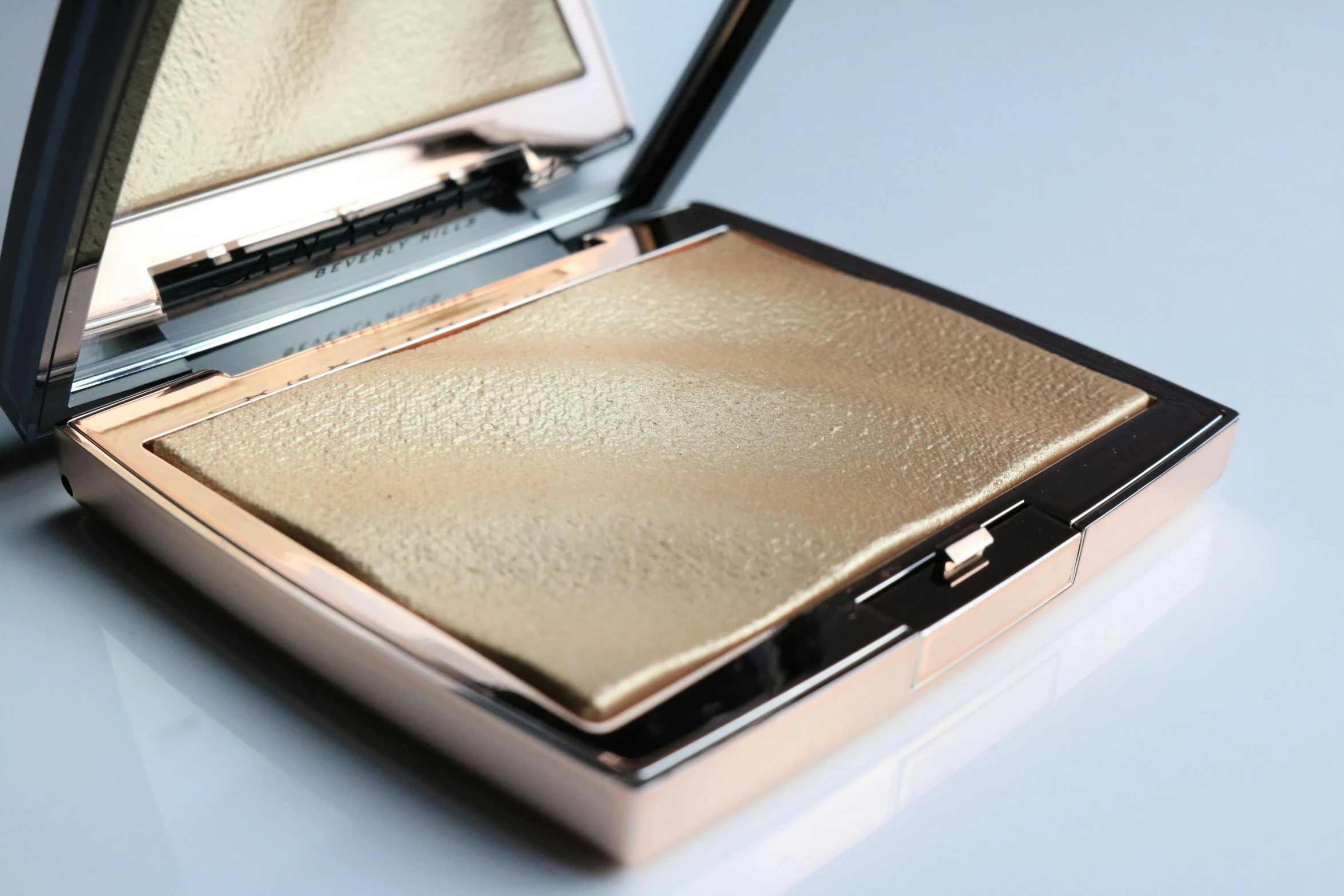 the compact is gold and has a metal lid