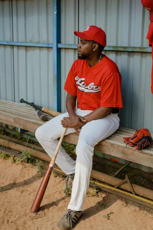 a baseball player is sitting with a baseball bat