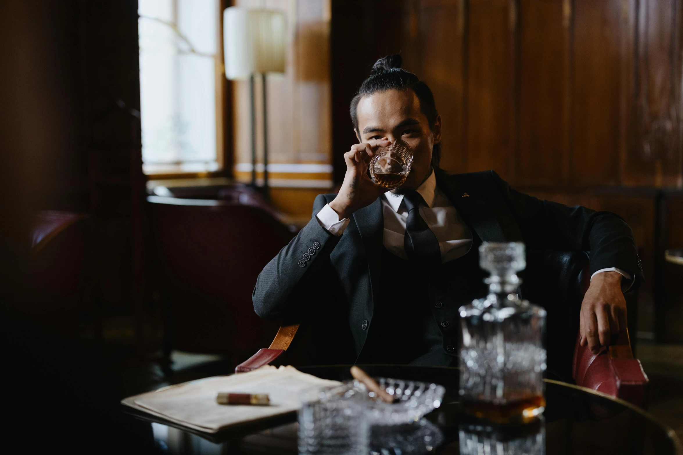 a man in a suit smoking a cigarette while sitting at a table