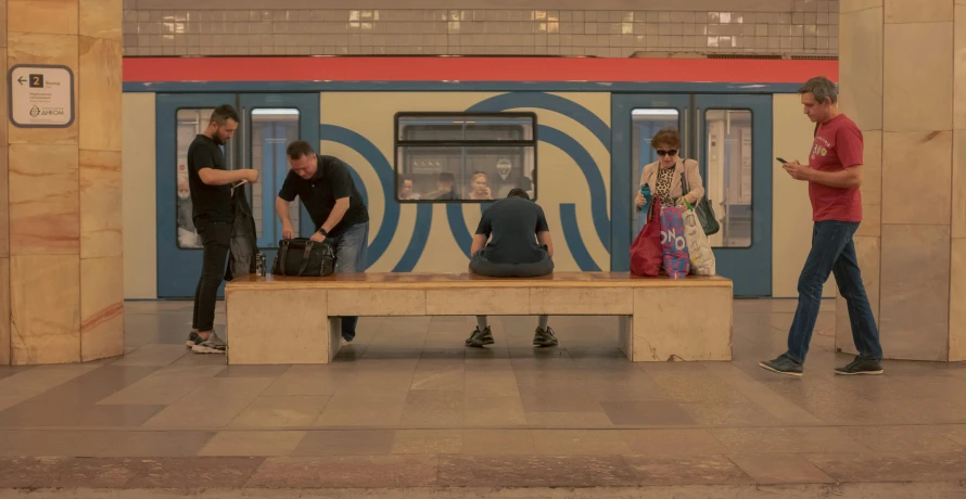 a group of people stand around a bench at a train station