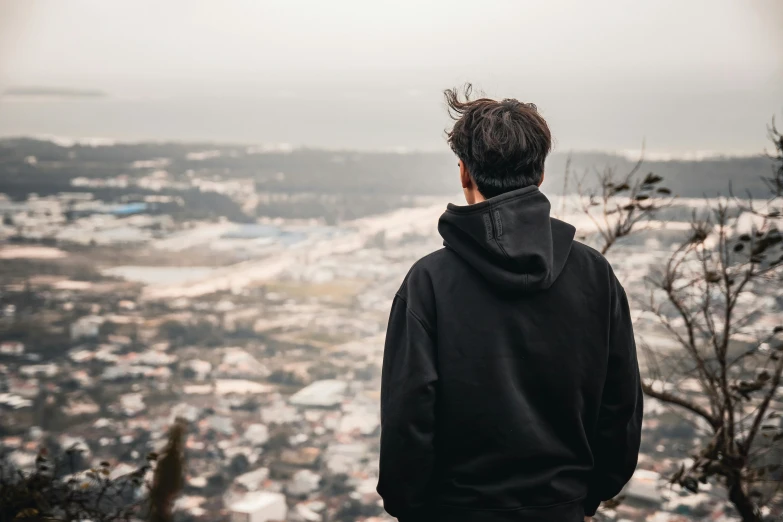 a person in a black sweatshirt looking out on the city