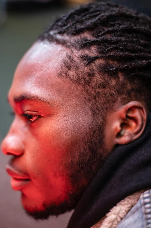 man with dreadlocks and a jacket looks intently at soing