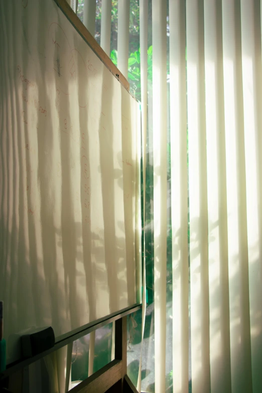 a white window curtain sits near a wooden desk