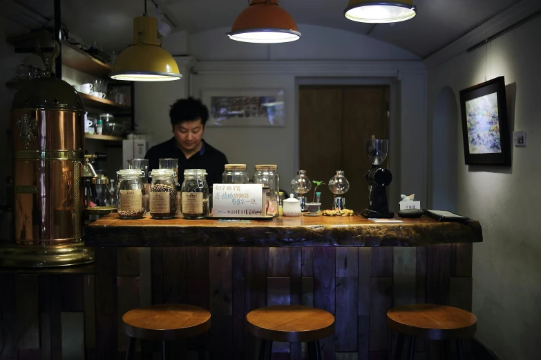 a bar with many jars and stools with a man behind the counter