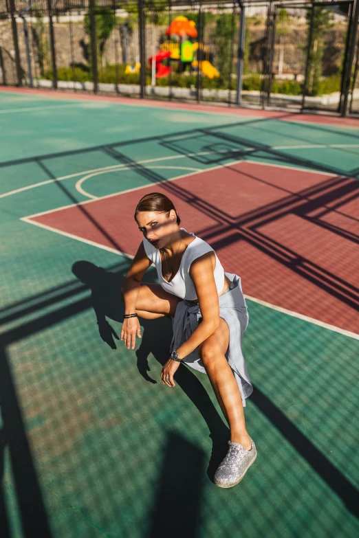 the woman sits on the tennis court in the shade