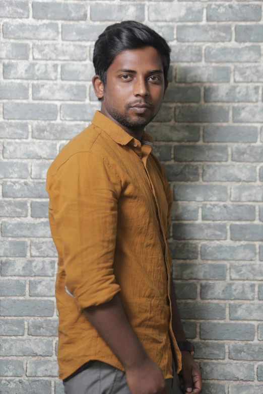 an indian man posing for a po in front of a brick wall