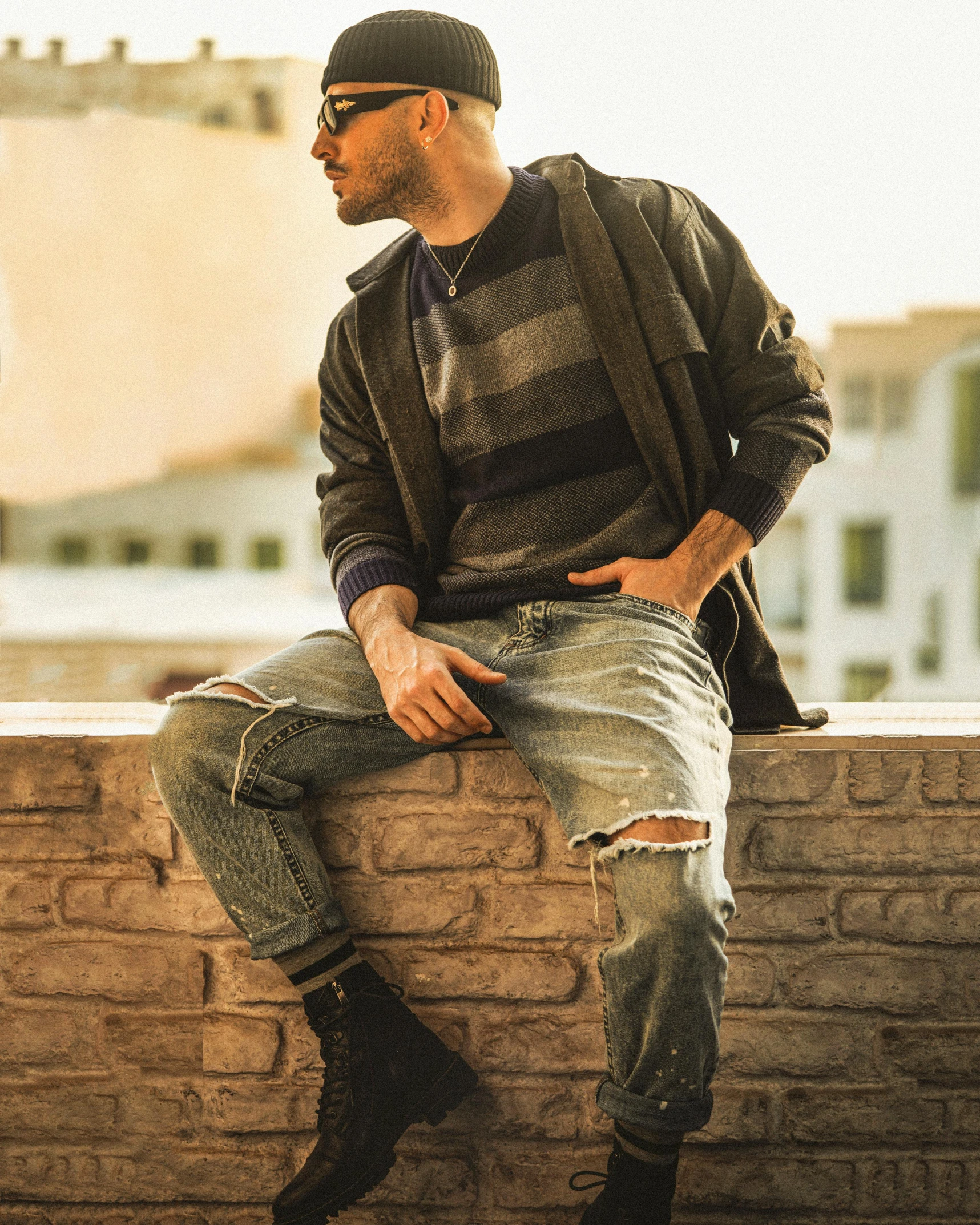 a man is sitting on a brick ledge wearing boots