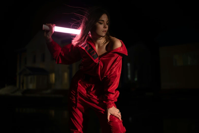 a woman holding a light saber in one hand and wearing red