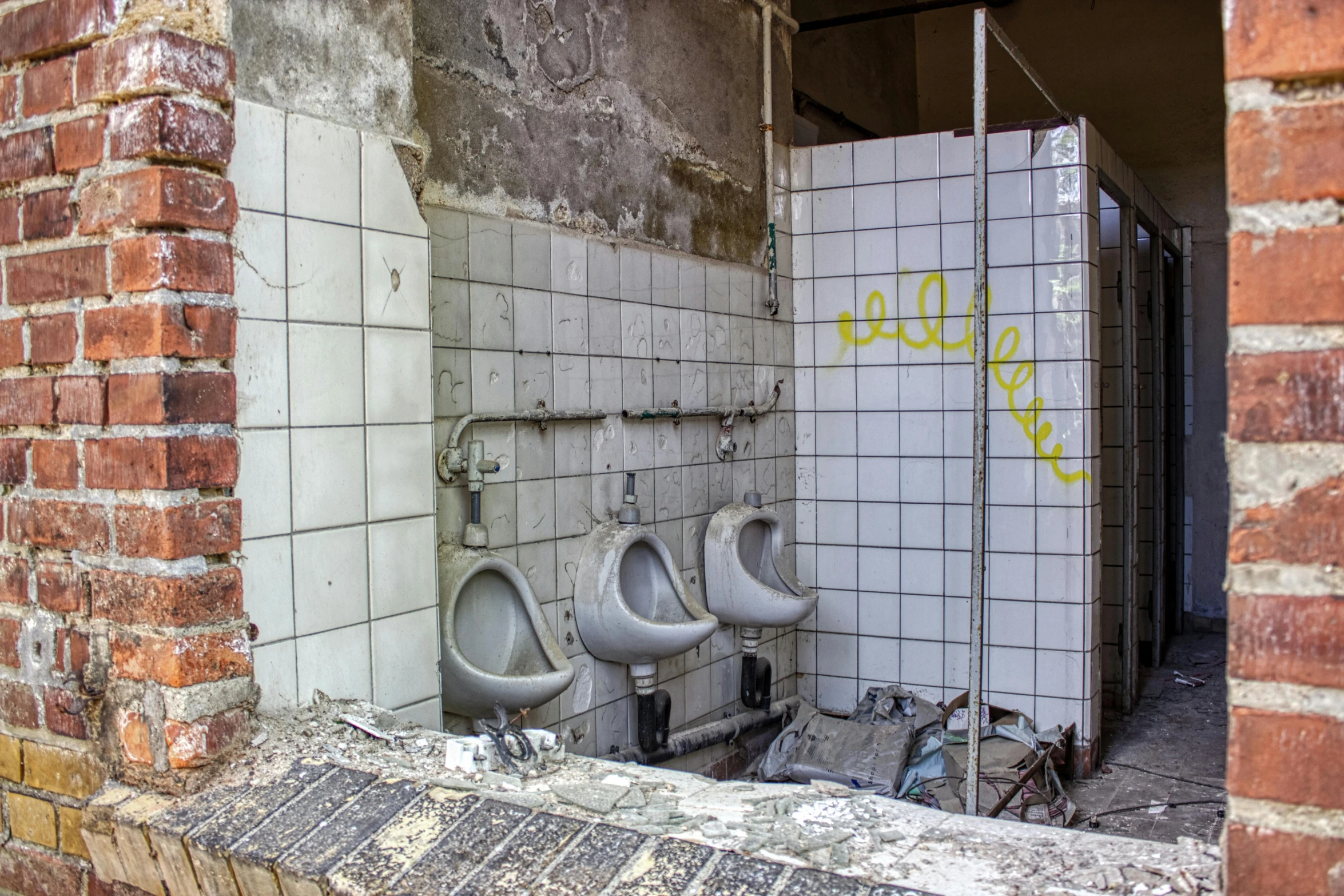 three urinals are standing next to an enclosed area