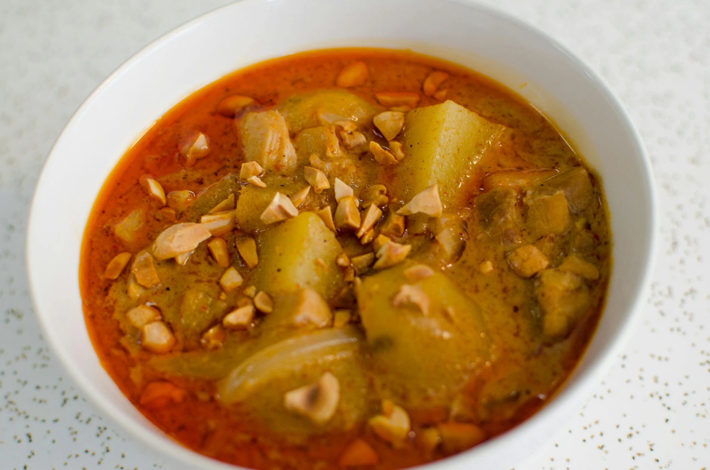 a bowl of chili with bananas is topped with peanuts