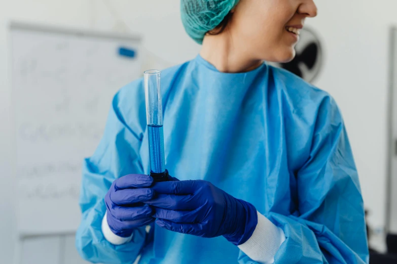 someone in scrubs and a cap and gloves is holding a tube with liquid