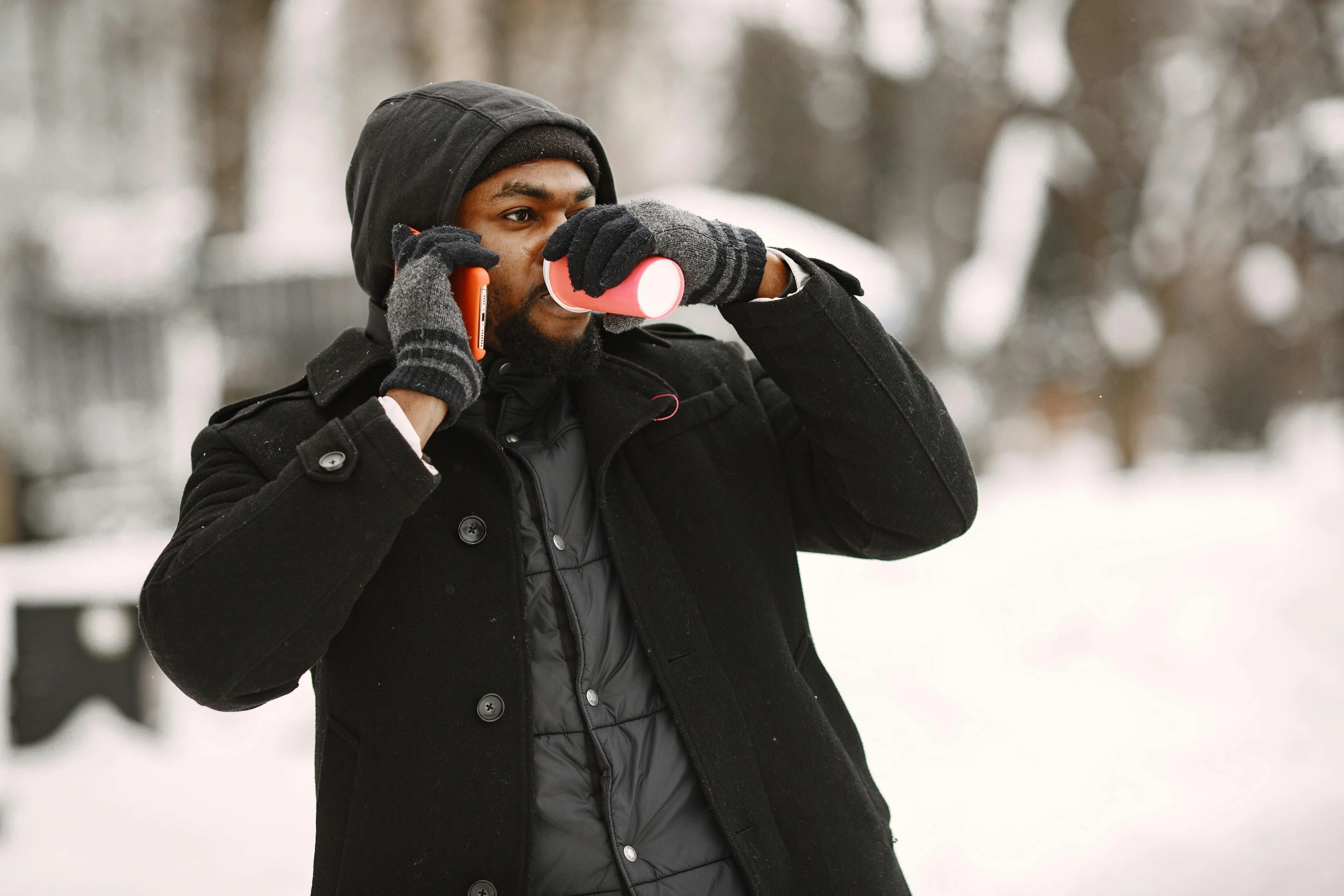 man in the winter coat talking on the phone while holding a bag