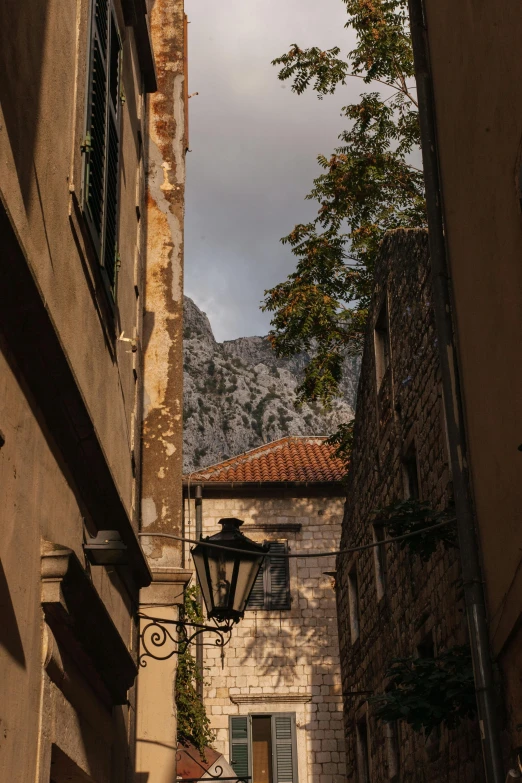 a lone streetlight between two buildings with a mountain in the background