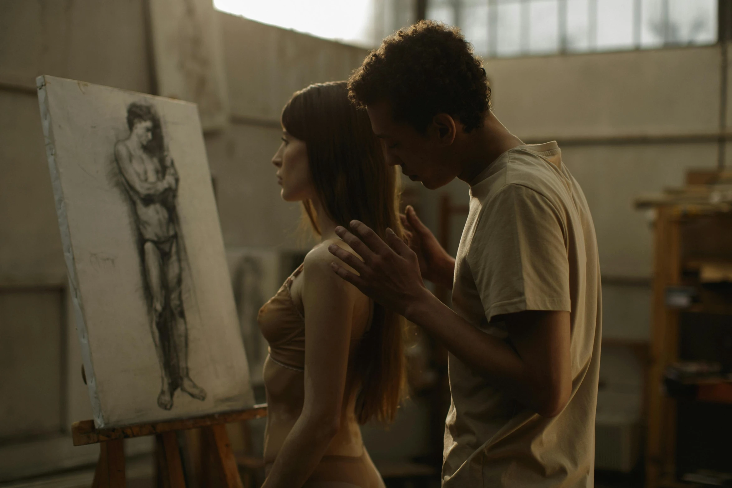 the woman stands between a man who is painting a figure