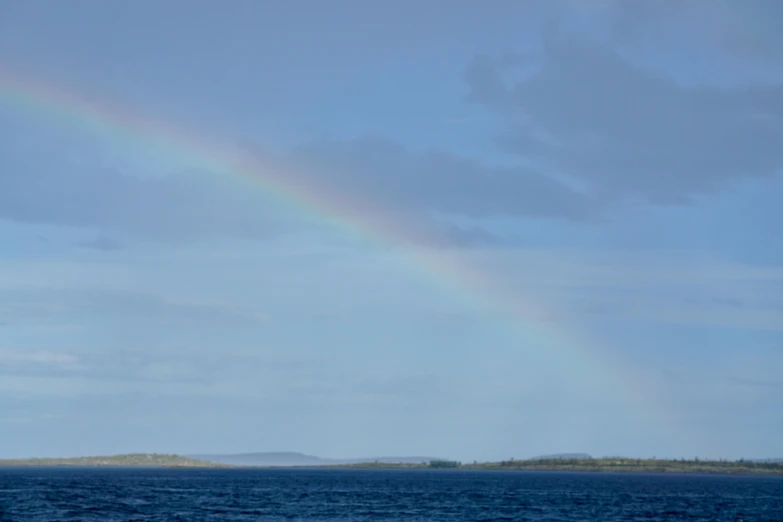 a rainbow that is in the sky over the water