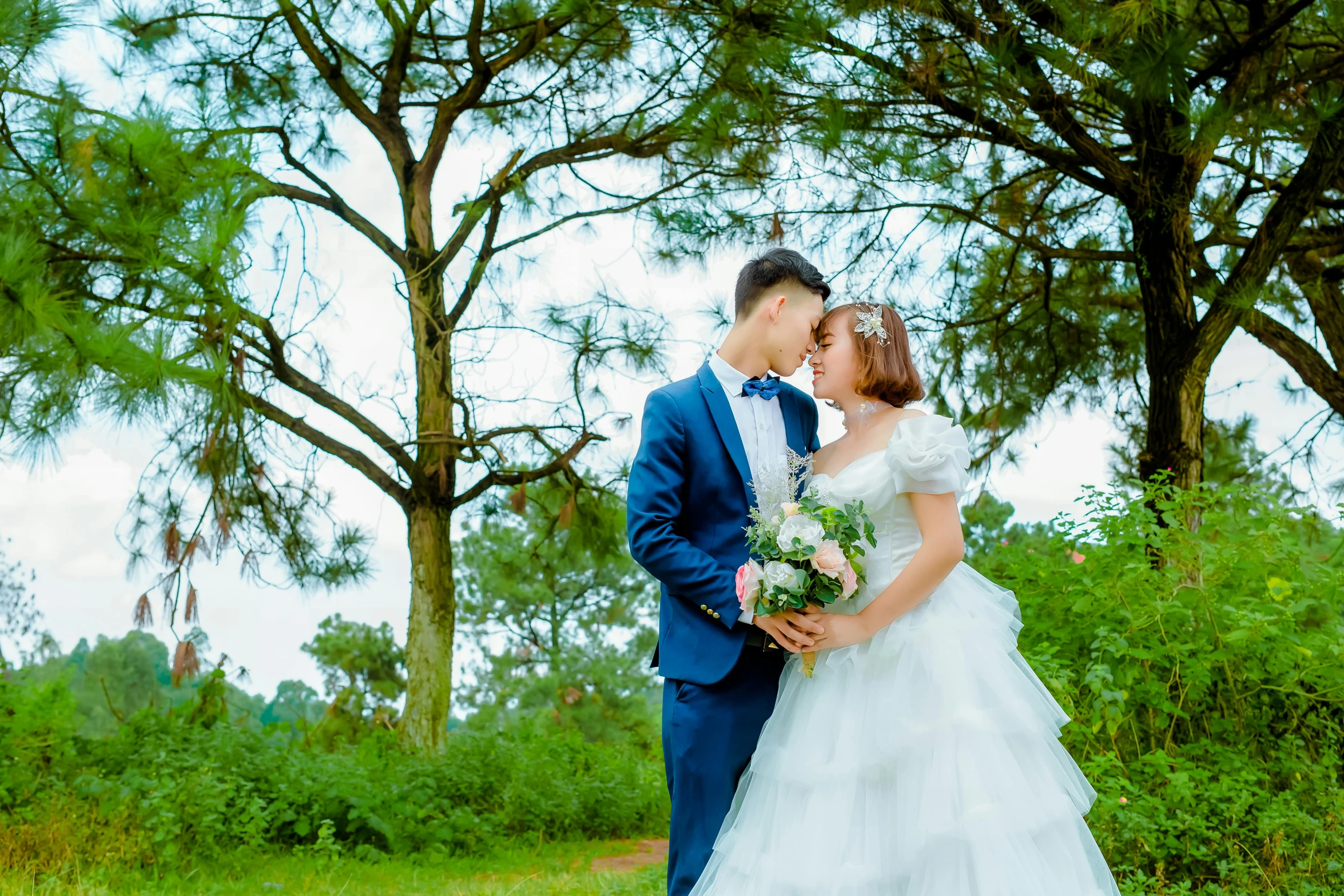 a bride and groom kissing in front of some trees