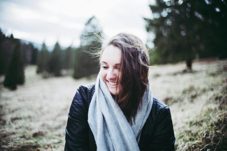 a woman wrapped in a scarf smiles in an outdoor area