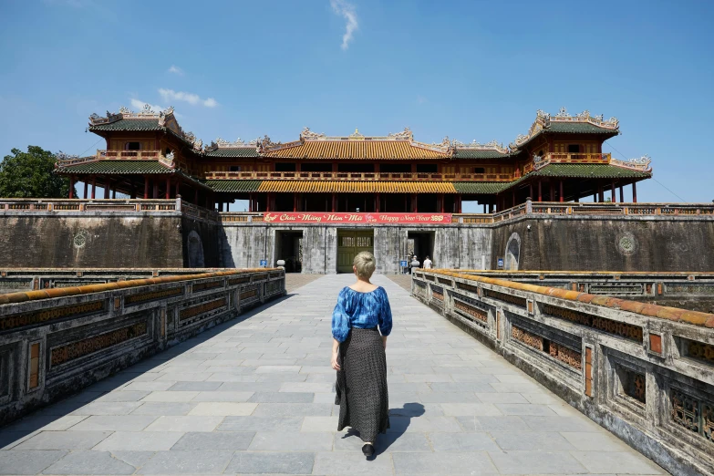 a woman in a dress walks across a walkway