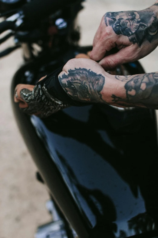 a hand with tattoos is holding a motorcycle handle