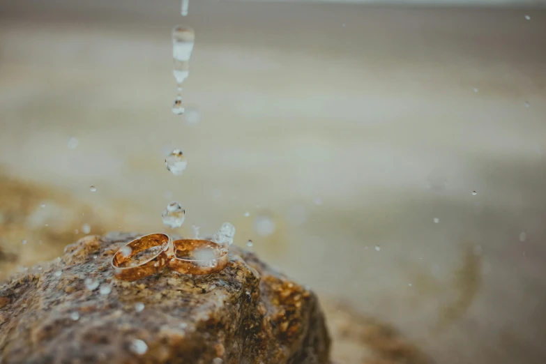 three wedding rings on top of a rock with water coming out