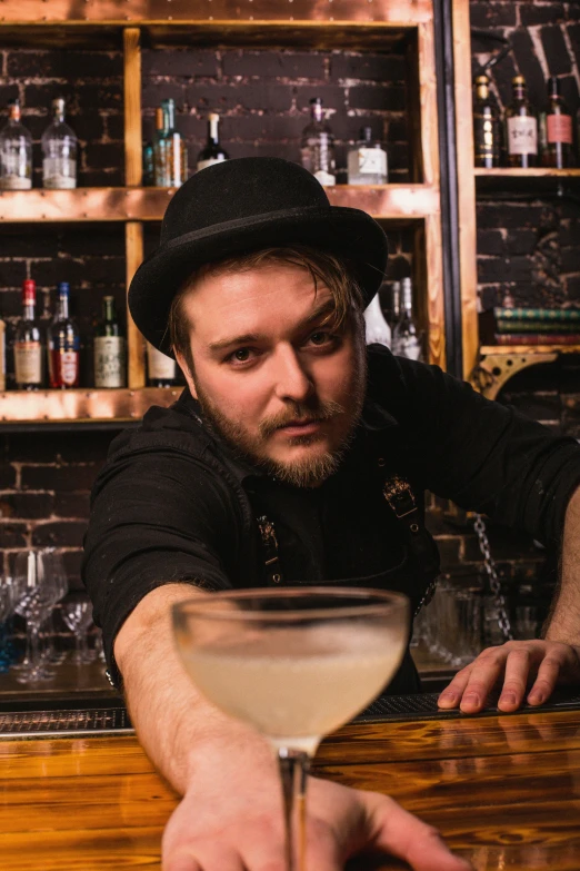 a man with a hat standing at a bar next to a martini