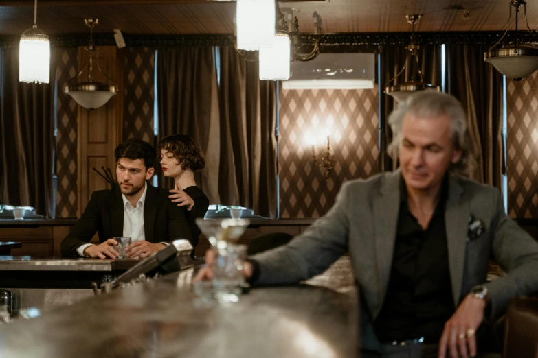 two men sitting at a bar in front of a woman