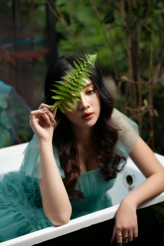 a woman with long dark hair holds a plant in her hand