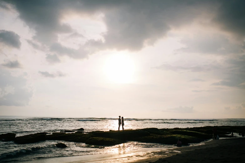 two people on the beach watching the sunset