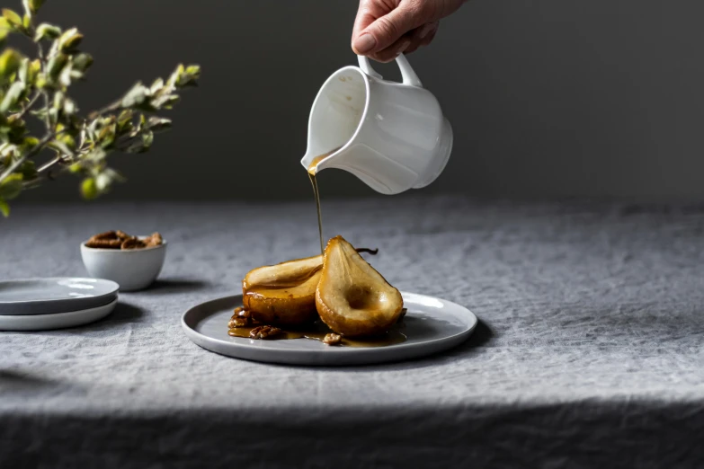 a person pouring syrup onto a plate topped with pear slices