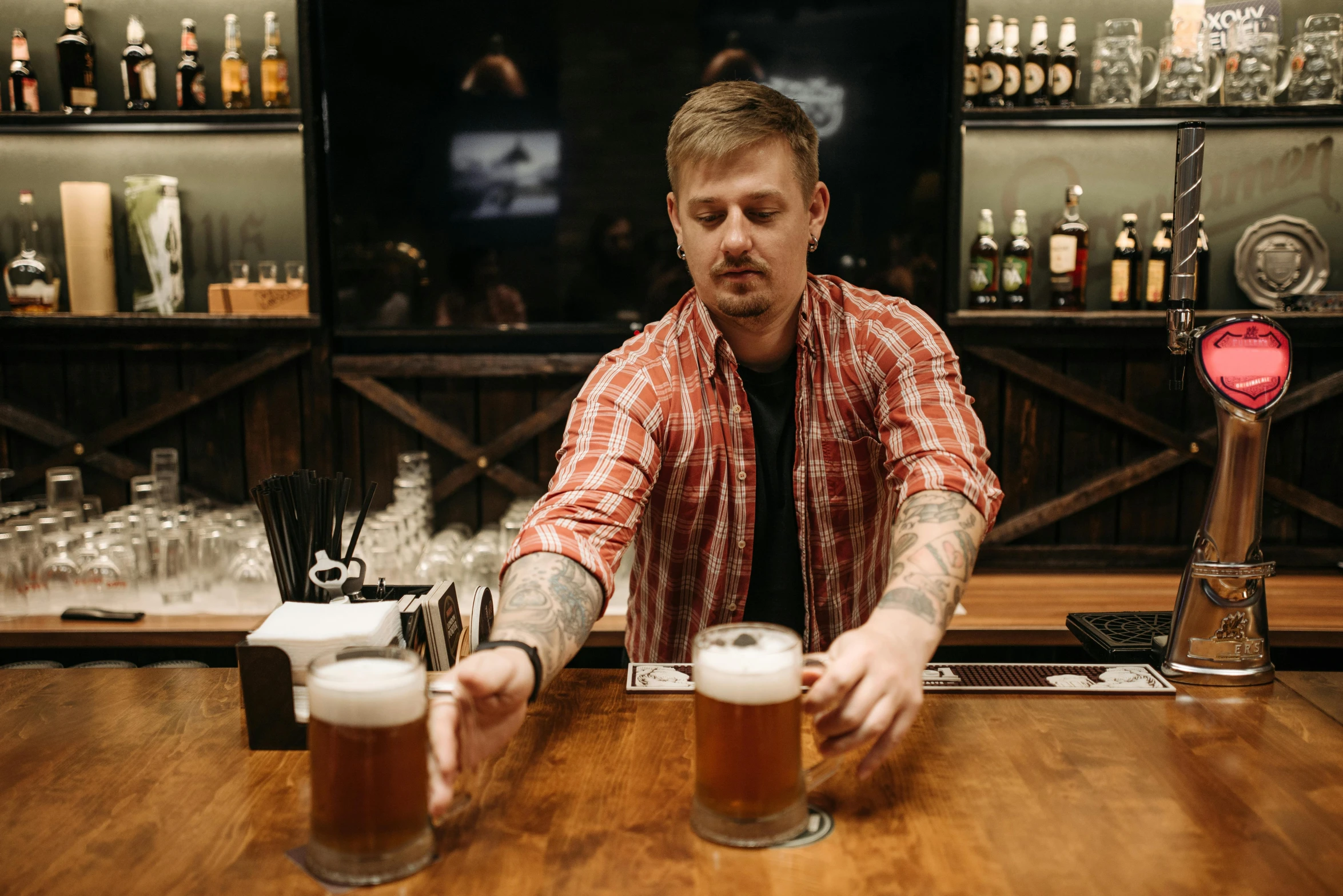 a man in a bar holding two mugs filled with beer