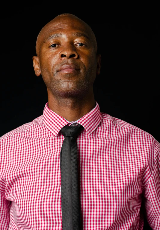 a man in a pink and white checkered shirt and black tie
