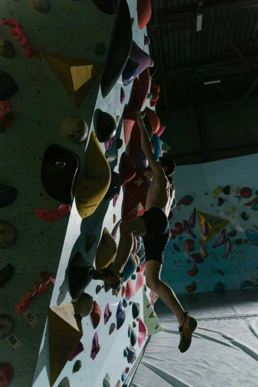 person climbing up a wall with a colorful paint design