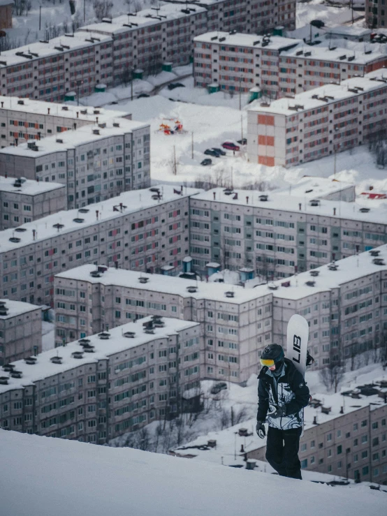 there is a snow boarder that stands in front of a lot of buildings