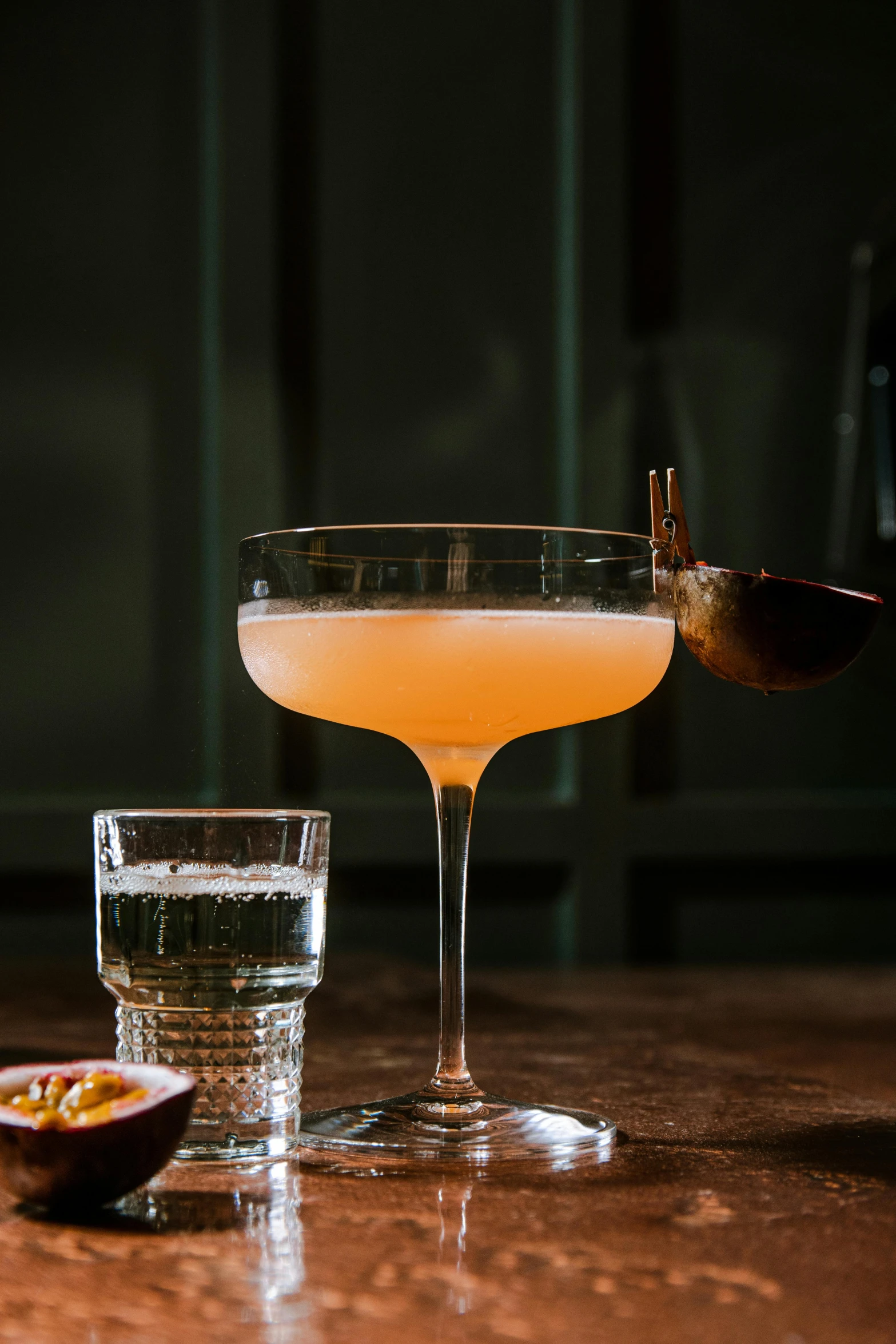 two glasses are sitting on the table with one drink being filled