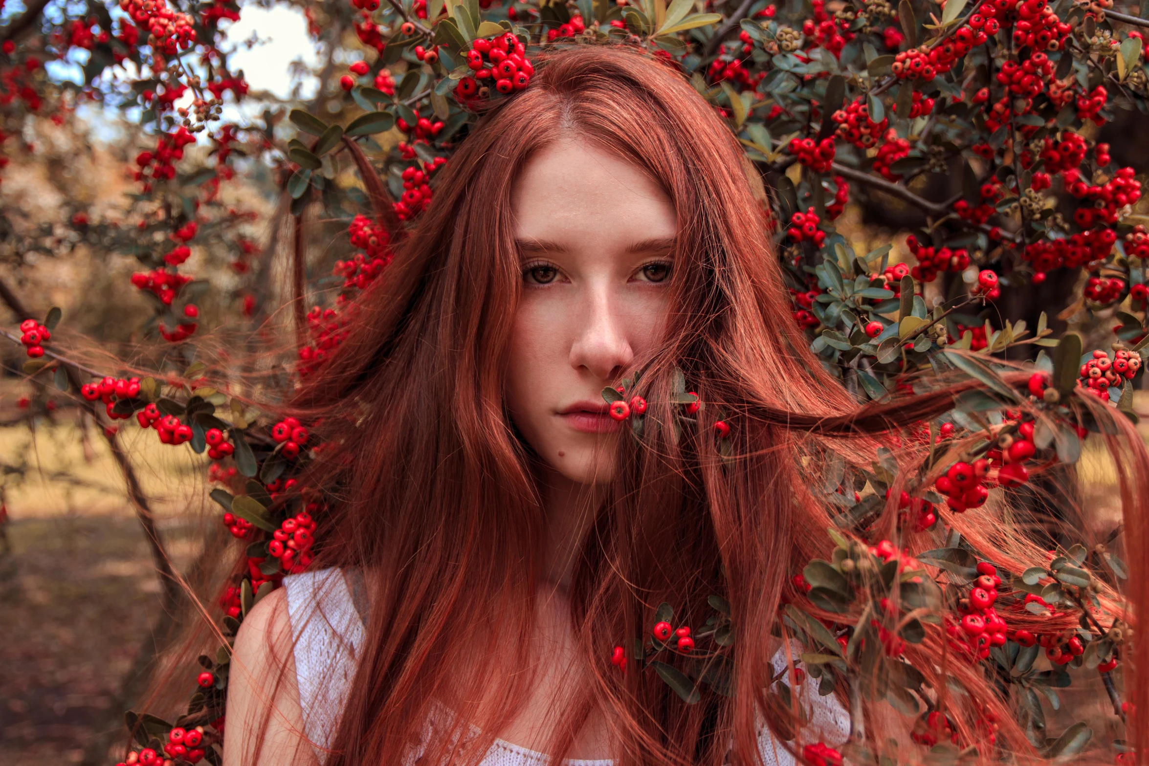 the woman with red hair is standing under a bush