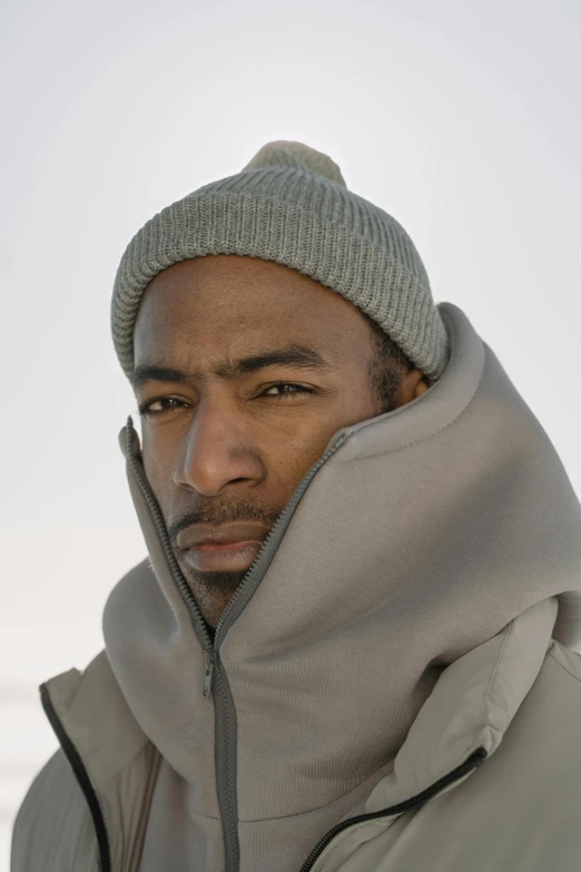 a young man wearing a knit cap and gray coat