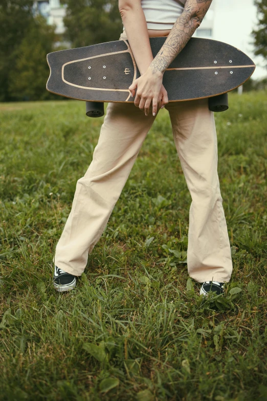 a woman with tattoos holding a skateboard in the grass