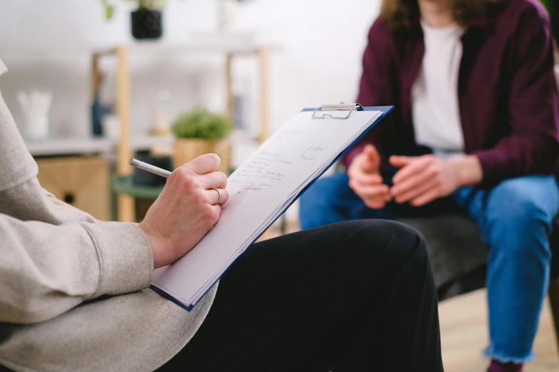 woman sitting down next to another person holding a clipboard